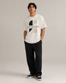Person wearing a white t-shirt with a logo and text, standing against a plain background