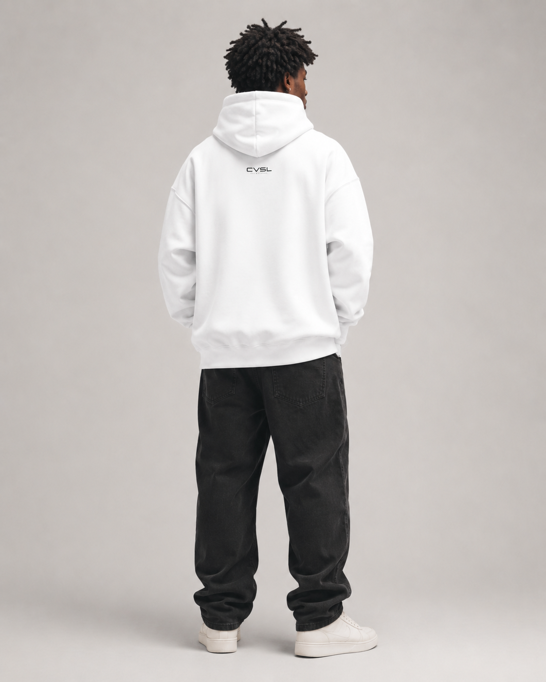 Person wearing a white hoodie and black pants on a gray background