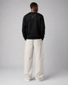 Person wearing a black sweatshirt with text on the back, standing against a plain background