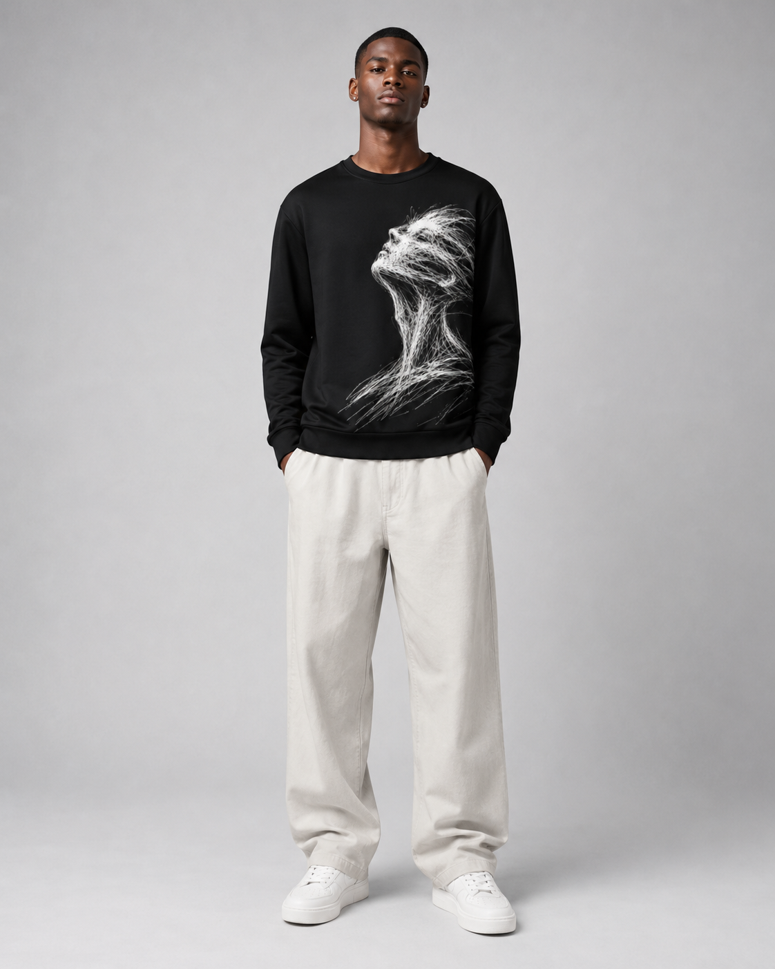 Person wearing a black sweatshirt with a white graphic design and white pants on a gray background