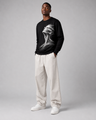 Man wearing a black sweatshirt with a white graphic design, white pants, and white shoes on a gray background