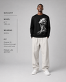 Man wearing a black sweatshirt with a graphic design on a gray background