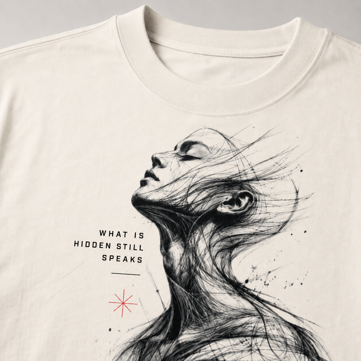 T-shirt with artistic design of a woman's face and text 'What is hidden still speaks' on a plain background