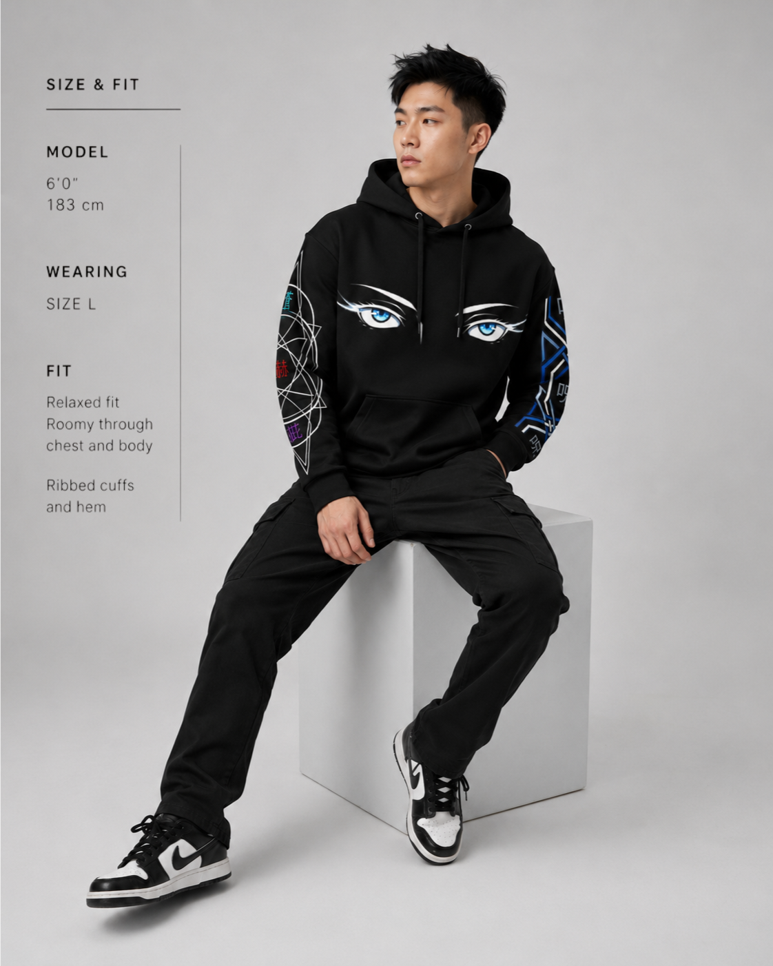 Person wearing a black hoodie with eye designs on a gray background