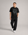 Man wearing a black 'Champion' t-shirt and pants on a gray background
