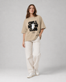Person wearing a beige t-shirt with 'Chill Brew Club' text on a plain background