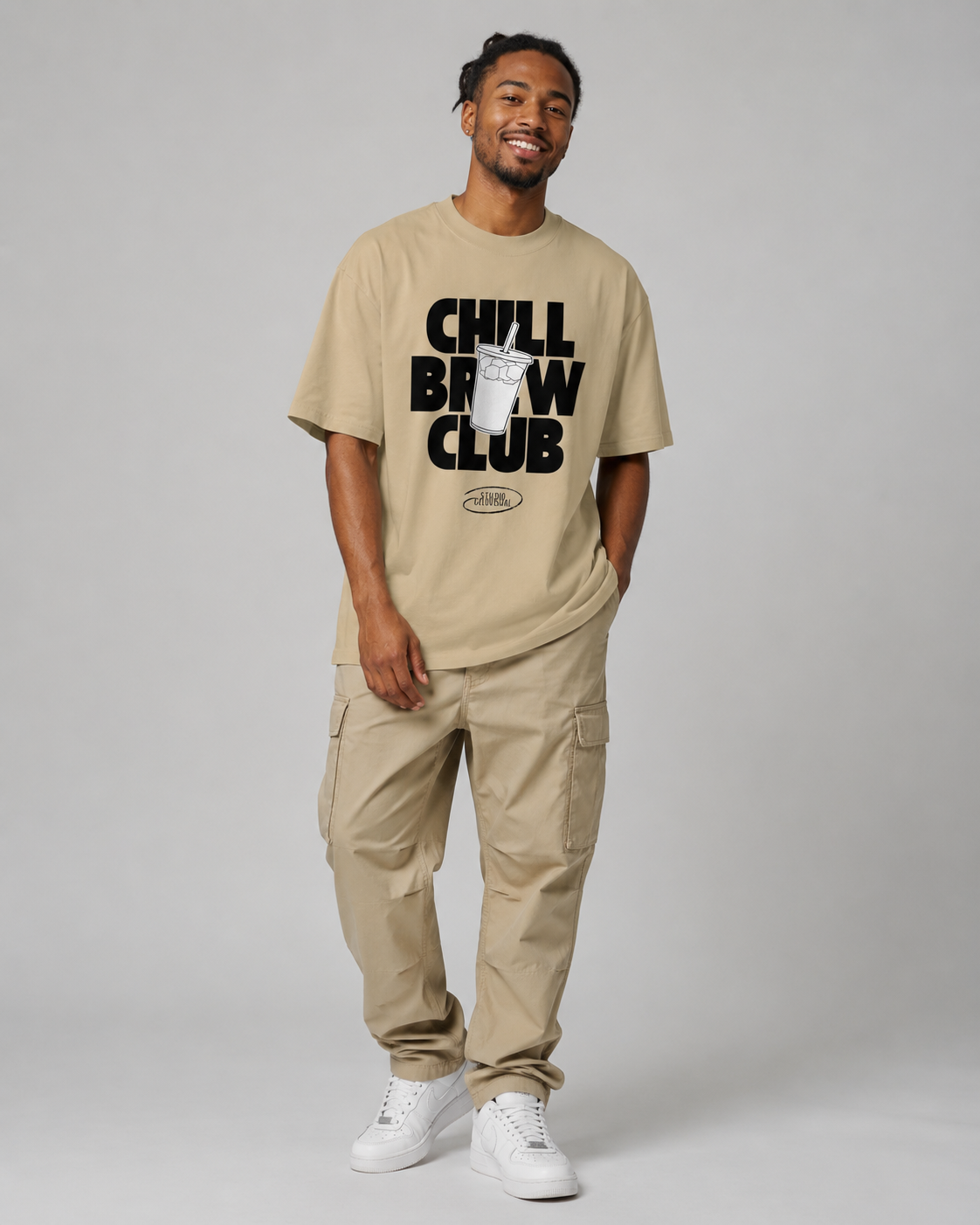 Man wearing a beige t-shirt with 'Chill Brew Club' text and cargo pants on a gray background