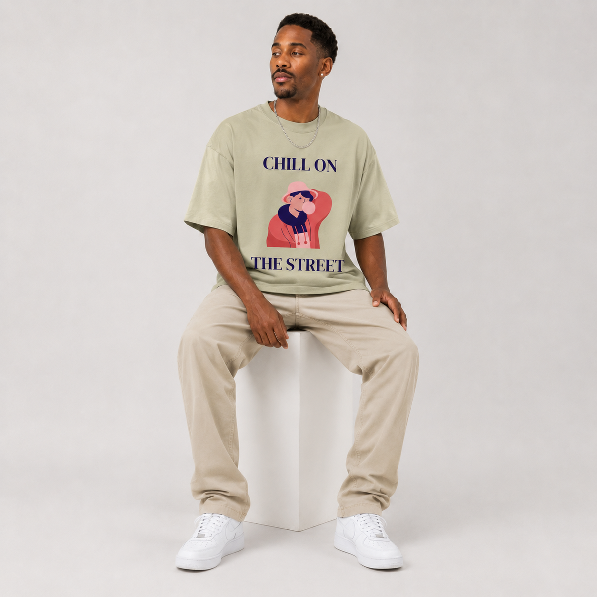 Person wearing a t-shirt with 'Chill on the Street' graphic and text, sitting on a white stool against a plain background.