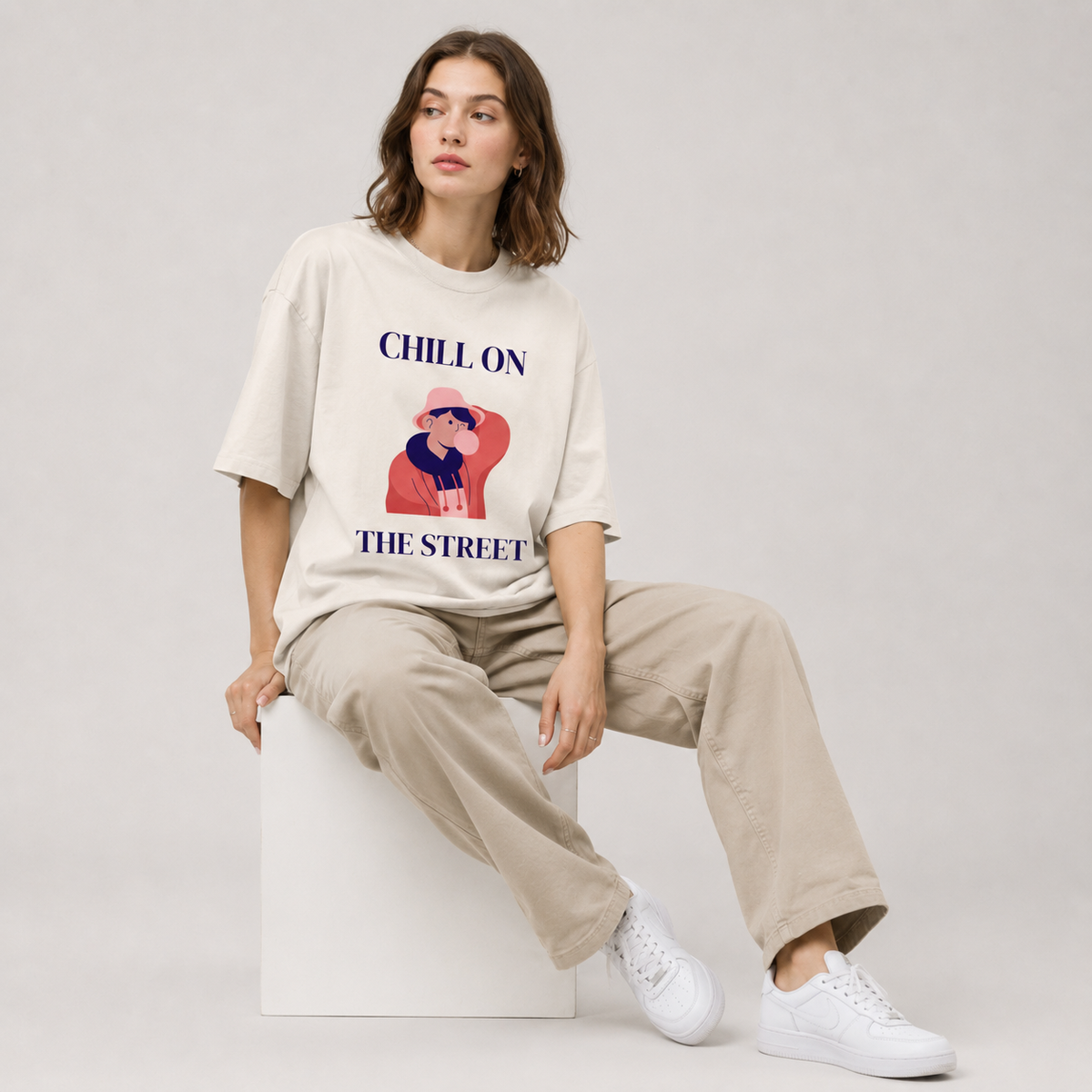Person wearing a 'Chill on the Street' t-shirt sitting on a white stool against a plain background