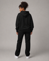 Person wearing a black hoodie and pants set on a gray background