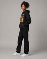 Person wearing a black hoodie with colorful graphics and black pants on a gray background