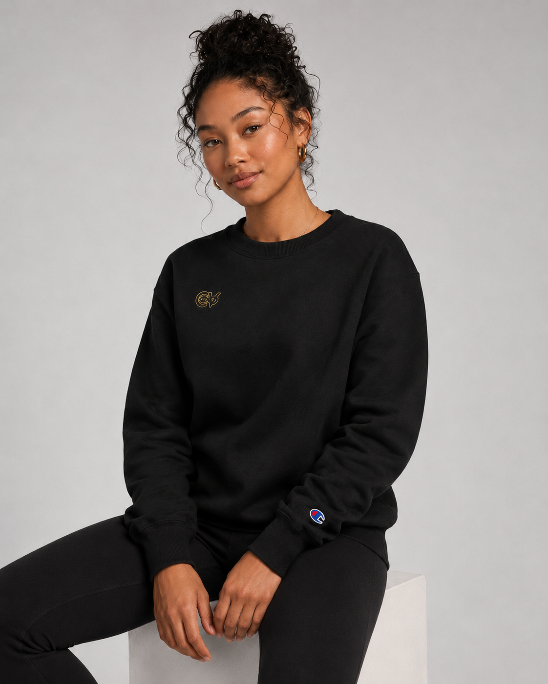 Person wearing a black sweatshirt with a logo on a gray background