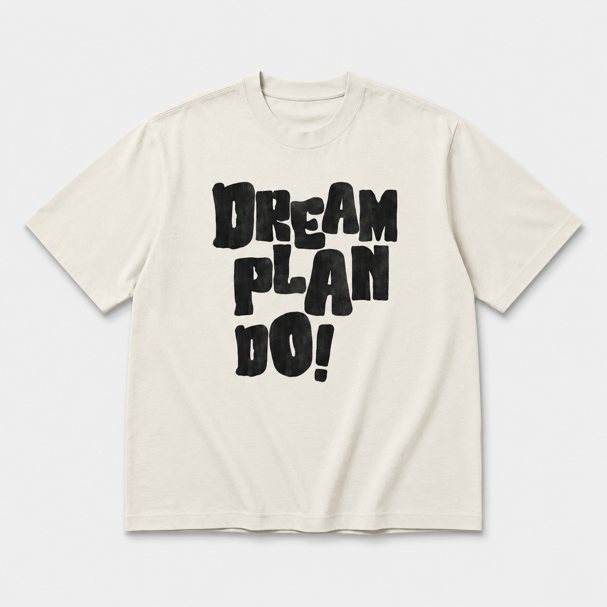 Beige t-shirt with 'Dream Plan Do!' text on a white background