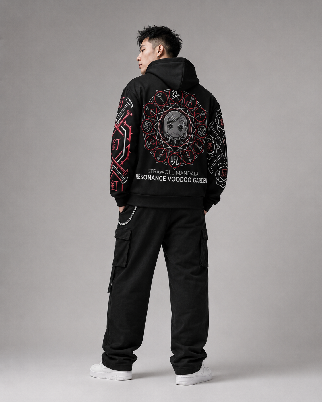 Person wearing a black hoodie with intricate designs on the back, standing against a gray background