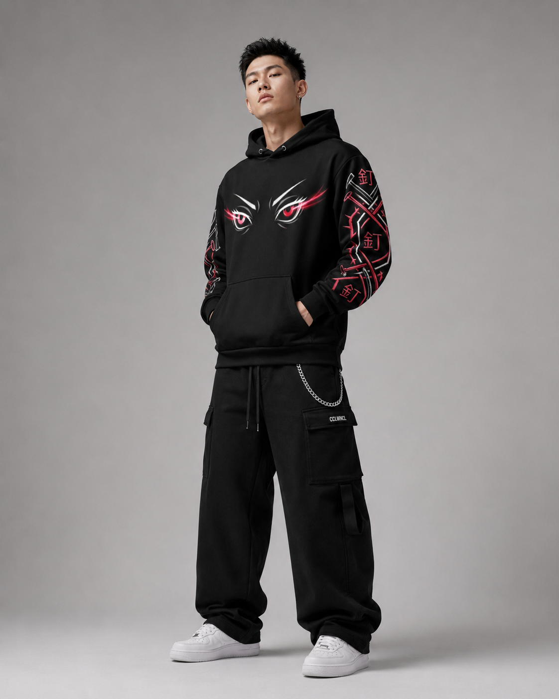 Person wearing a black hoodie and pants with red and white designs on a gray background