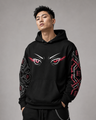 Person wearing a black hoodie with eye design and red accents on a gray background