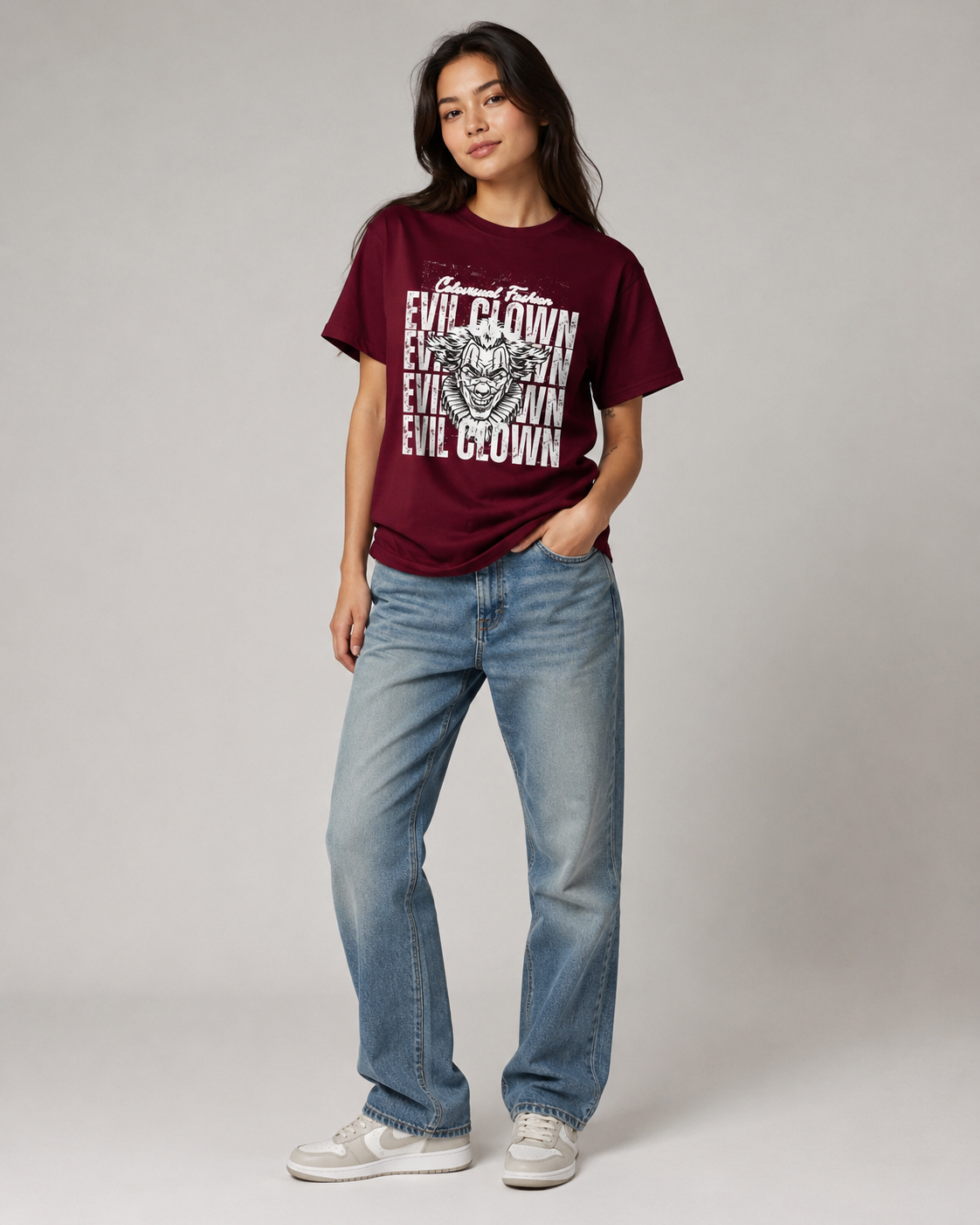 Person wearing a maroon t-shirt with graphic design and text, paired with blue jeans on a plain background