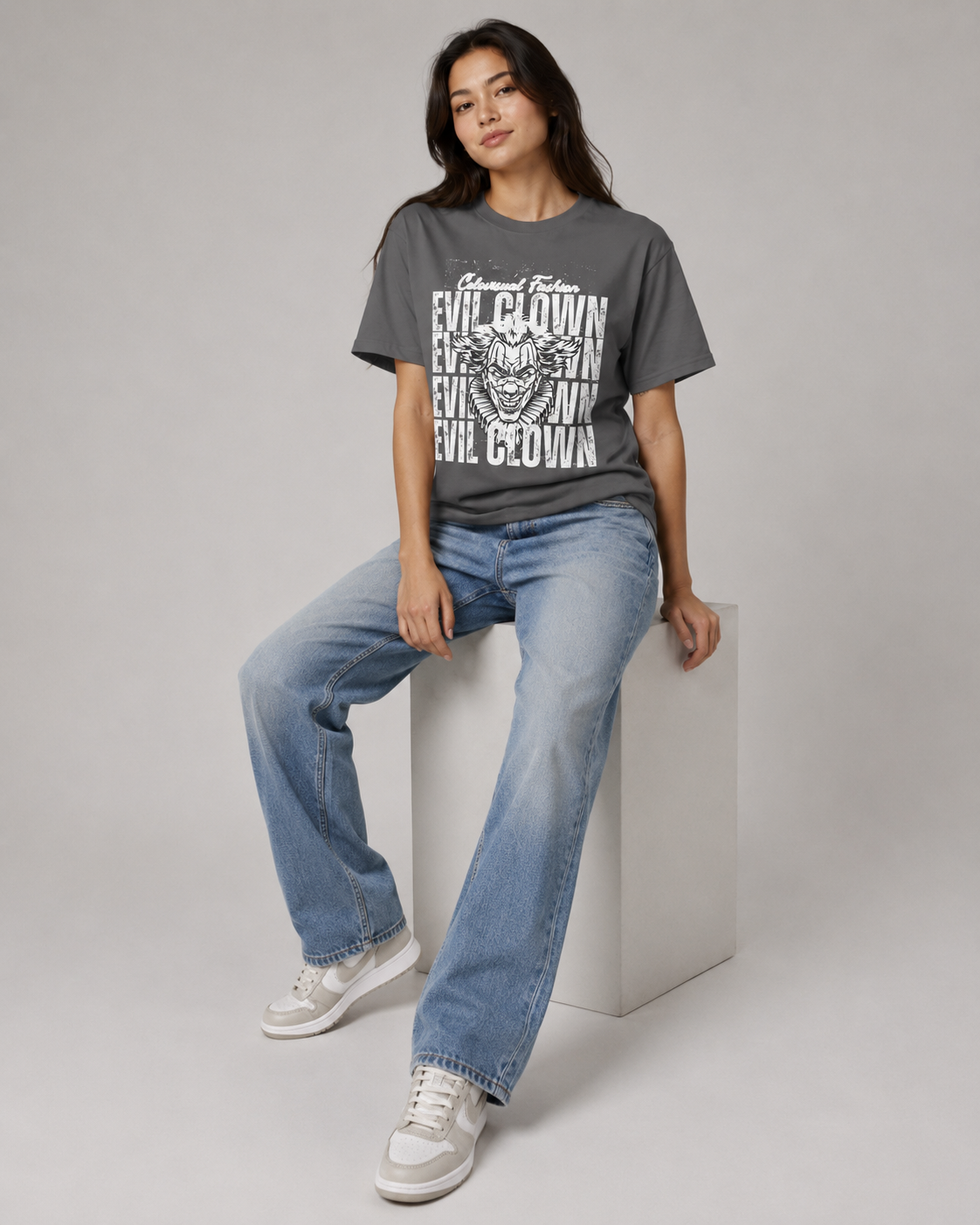 Person wearing a gray t-shirt with graphic design and blue jeans on a light gray background