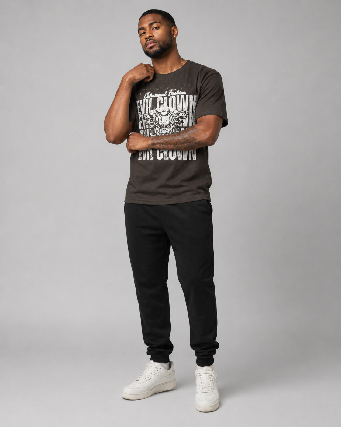 Man wearing a black t-shirt with graphic design and text, black pants, and white sneakers on a gray background