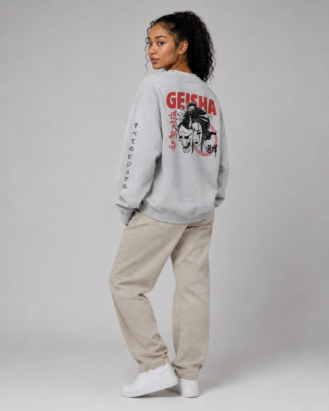 Person wearing a gray sweatshirt with 'Geisha' design and beige pants on a plain background