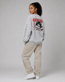 Person wearing a gray sweatshirt with 'Geisha' design and beige pants on a plain background