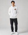 Person wearing a white hoodie with red text and black pants on a gray background