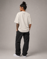 Person wearing a beige t-shirt and black pants on a gray background