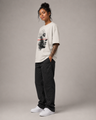 Person wearing a white t-shirt with a graphic design, black pants, and white sneakers on a gray background
