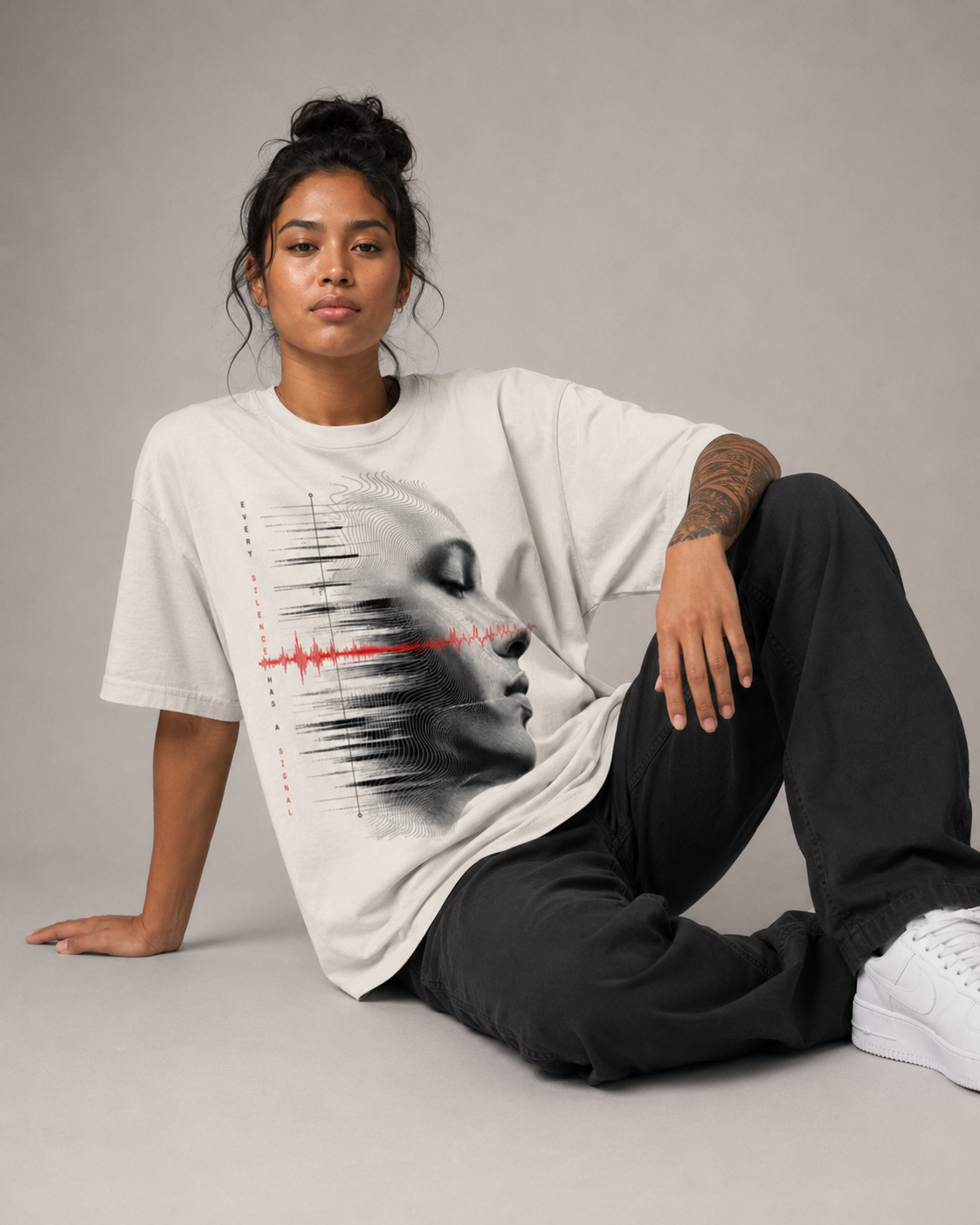 Person wearing a white t-shirt with a graphic design sitting on a gray background