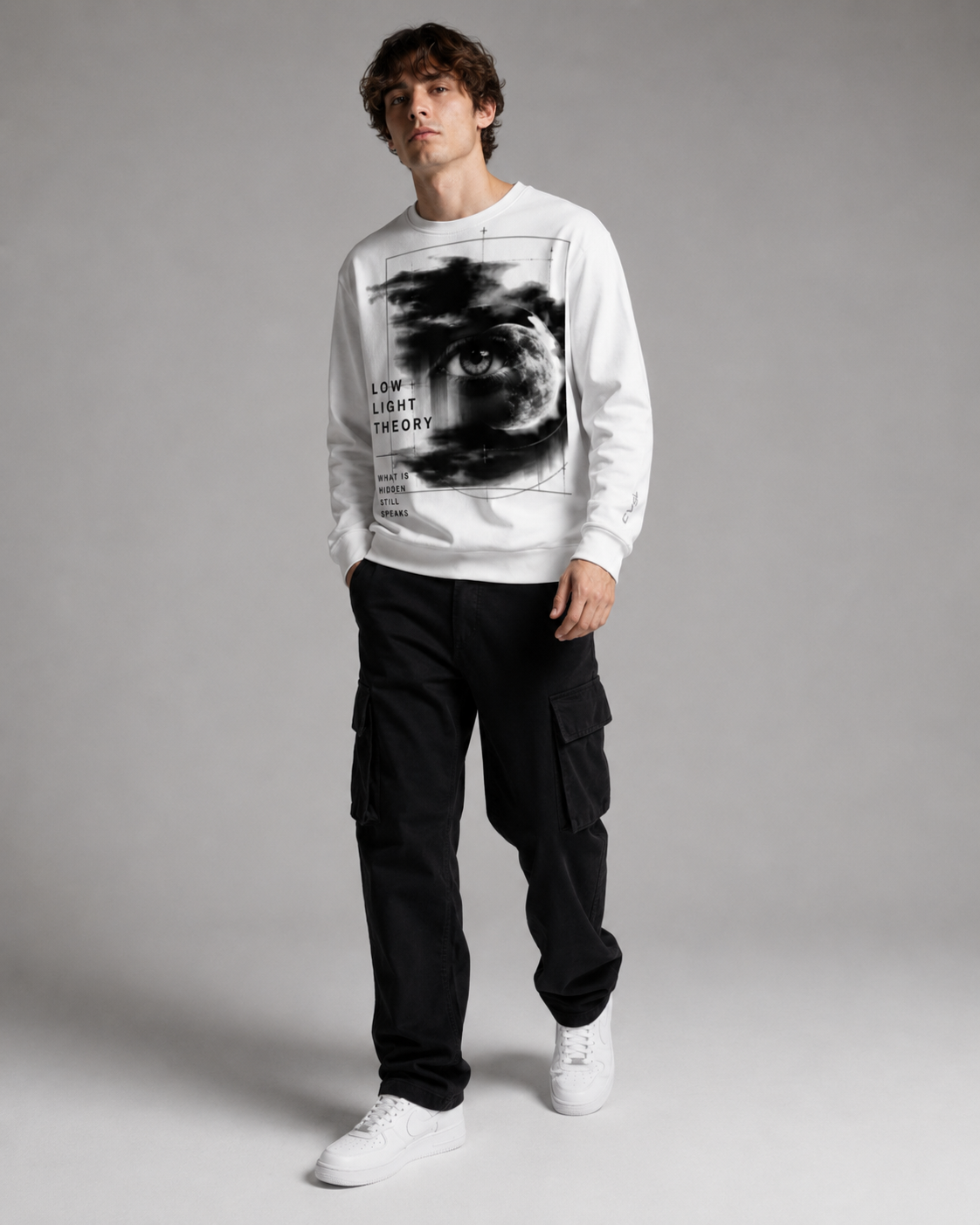 Person wearing a white sweatshirt with a graphic design and black pants on a gray background