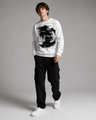 Person wearing a white sweatshirt with a graphic design and black pants on a gray background
