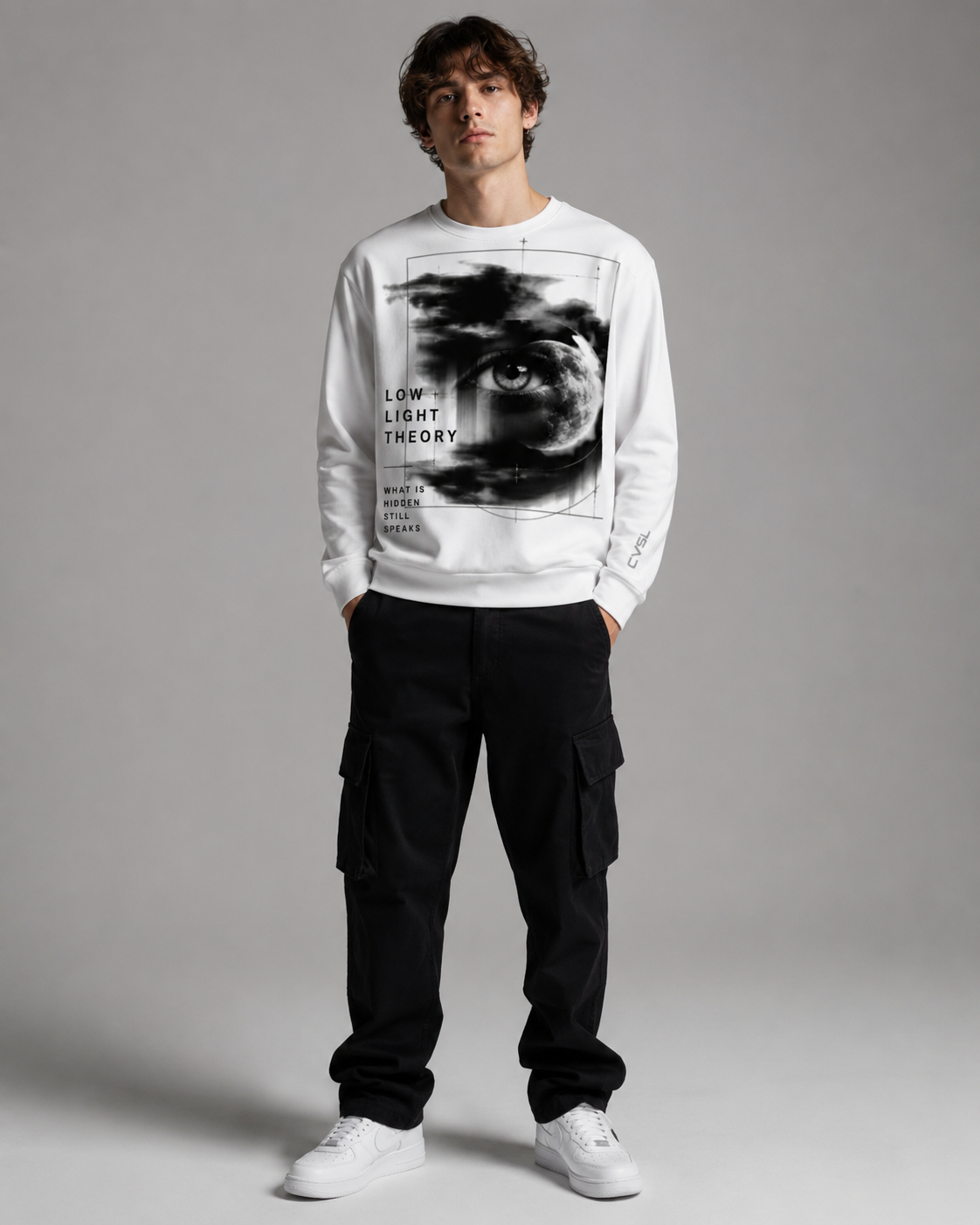 Person wearing a white sweatshirt with a graphic design and text, standing against a plain background