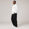 Person wearing a white hoodie and black pants on a plain background