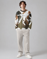 Person wearing a patterned sweater and light pants on a gray background
