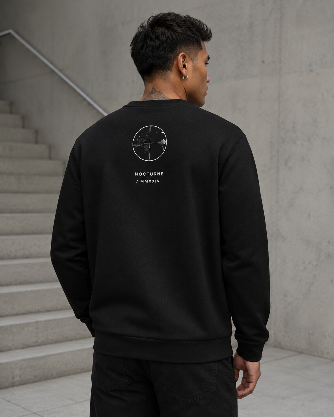 Person wearing a black sweatshirt with a logo on the back, standing on a staircase.
