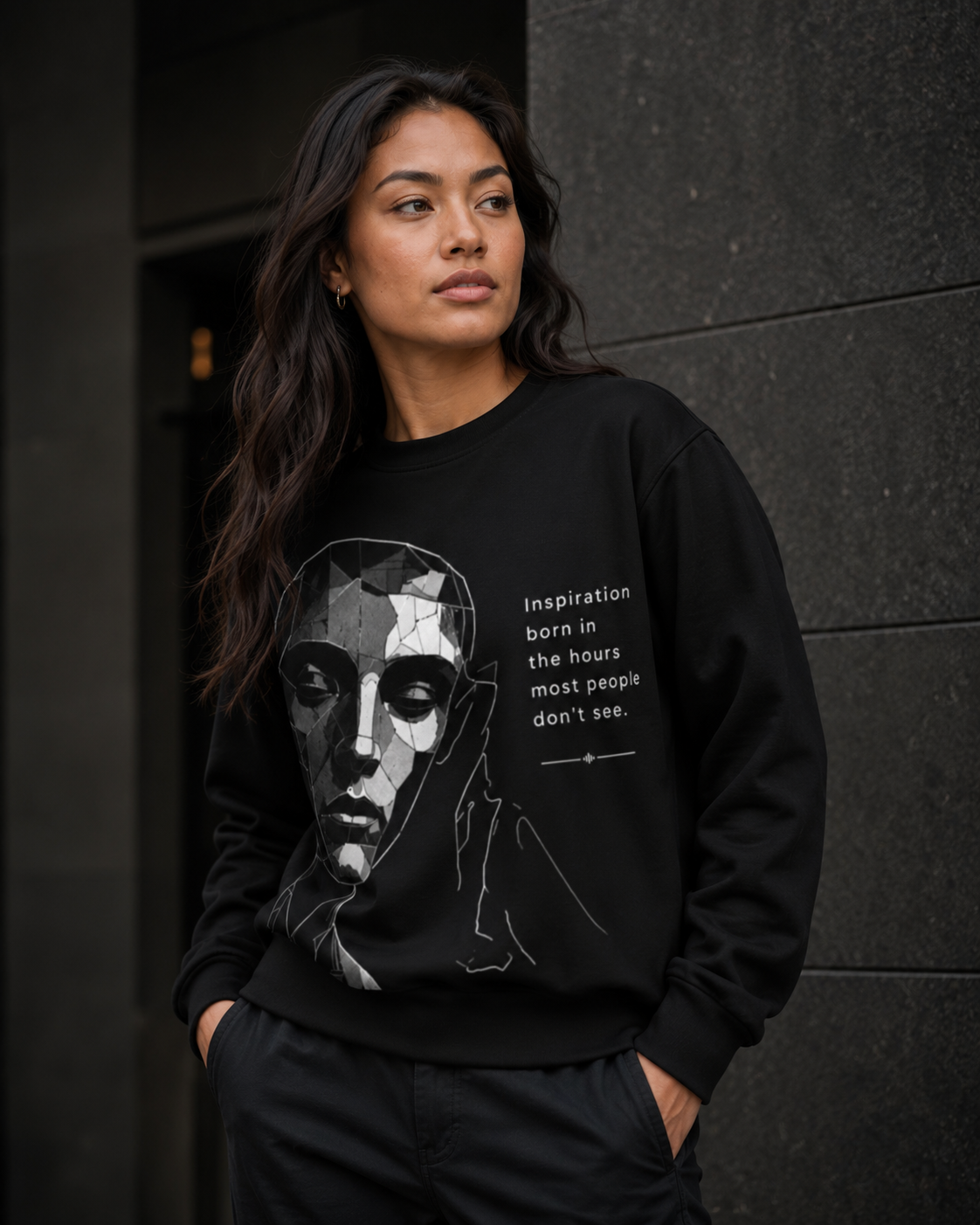 Woman wearing a black sweatshirt with a graphic design and text against a dark background