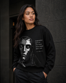 Woman wearing a black sweatshirt with a graphic design and text against a dark background