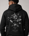 Black hoodie with a rose design on the back, worn by a person against a neutral background