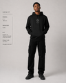 Person wearing a black hoodie and cargo pants with size and fit information on the left.