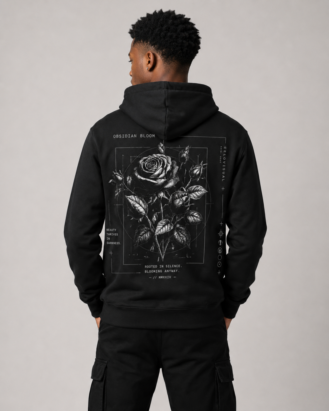 Person wearing a black hoodie with a rose design on the back against a gray background