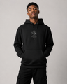 Person wearing a black hoodie with a logo on a gray background
