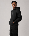 Person wearing a black hoodie with a logo on a gray background