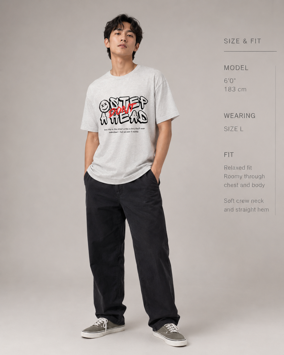 Man wearing a white t-shirt with text and black pants on a gray background