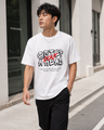 Man wearing a white t-shirt with black text and graphics on a city street.