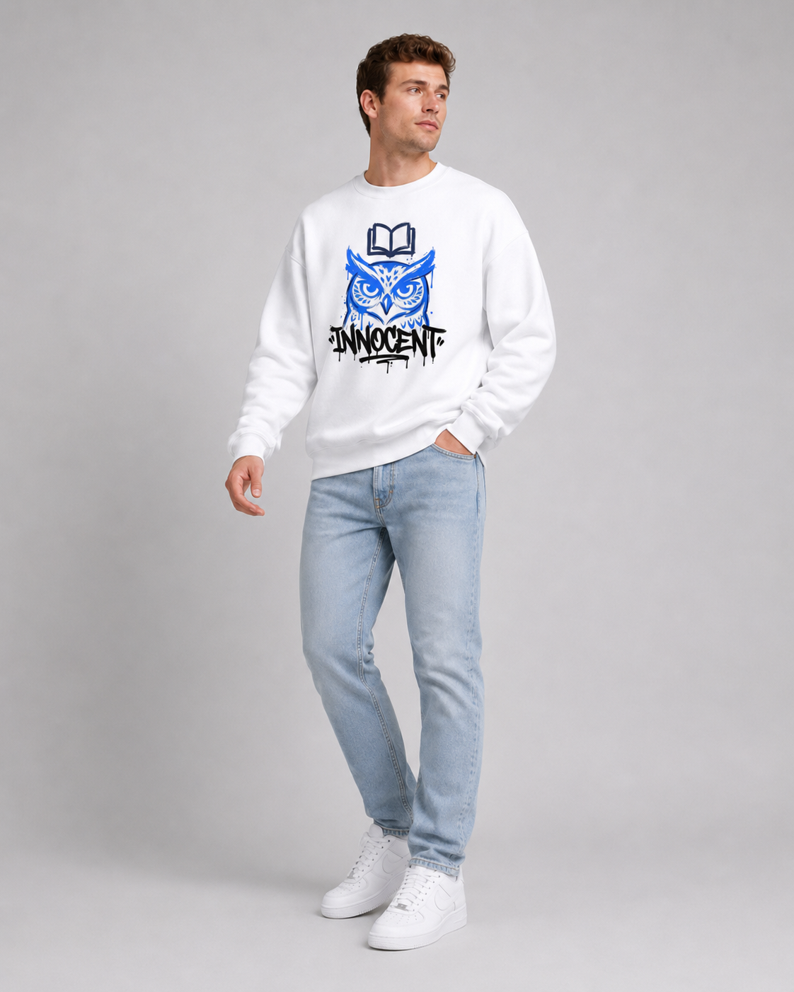 Person wearing a white sweatshirt with a graphic design and light blue jeans on a gray background