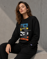 Woman wearing a black sweatshirt with colorful graphic design against a gray concrete wall.