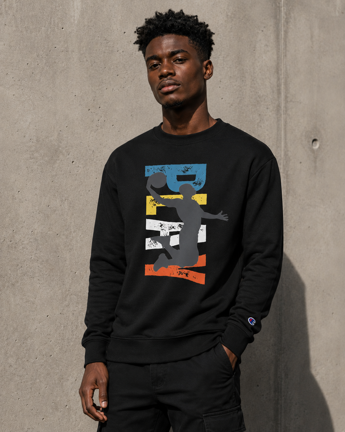 Man wearing a black sweatshirt with a graphic design against a concrete wall