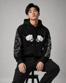 Person wearing a black hoodie with white fist designs on a gray background