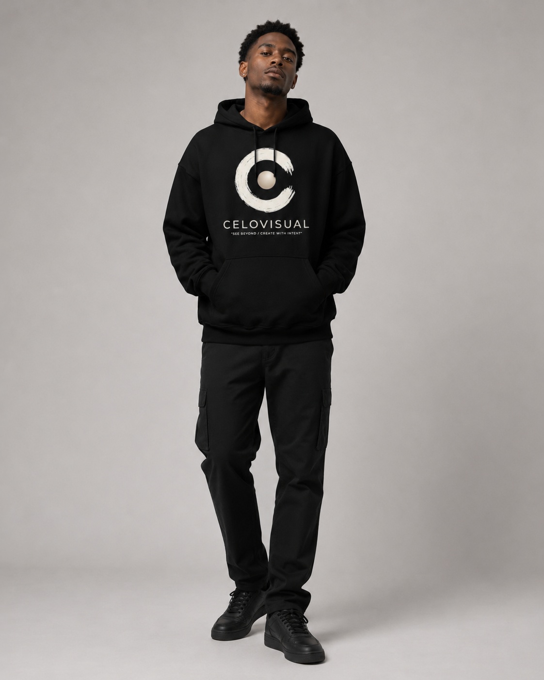 Person wearing a black hoodie with a logo and text, standing against a plain background