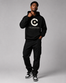 Person wearing a black hoodie with a logo and text on a gray background